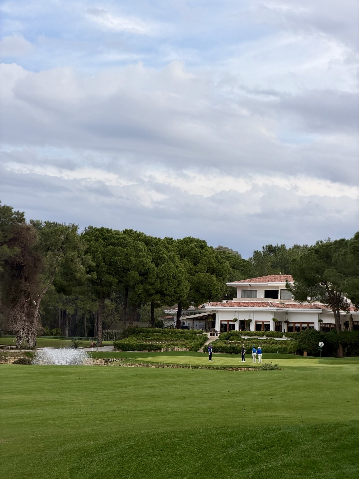 Golfers on a green beside a clubhouse